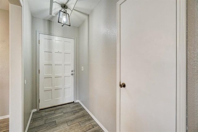 doorway featuring wood tiled floor and baseboards