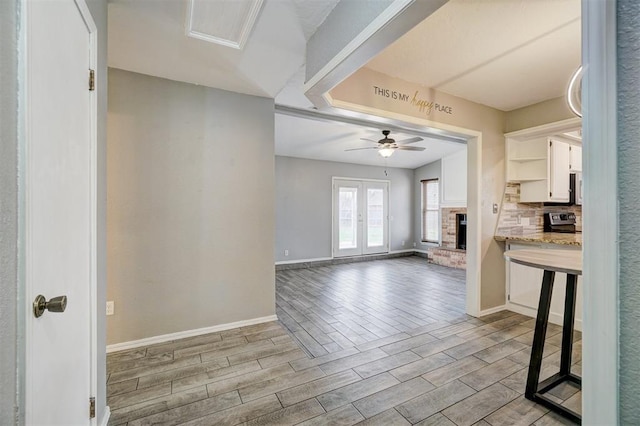 kitchen with wood finish floors, a fireplace, light countertops, decorative backsplash, and white cabinetry