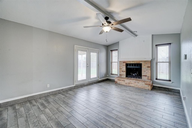 unfurnished living room featuring vaulted ceiling with beams, a fireplace, wood finished floors, and a wealth of natural light