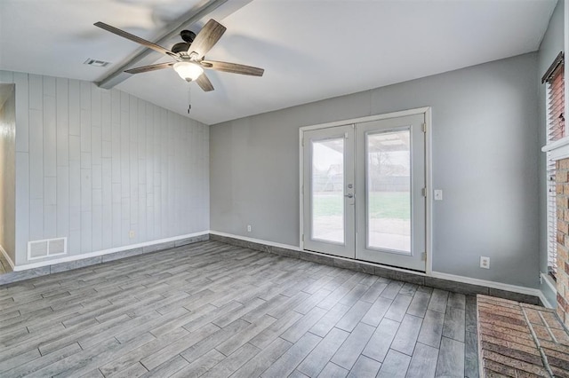 unfurnished room with visible vents, vaulted ceiling with beams, and wood finished floors