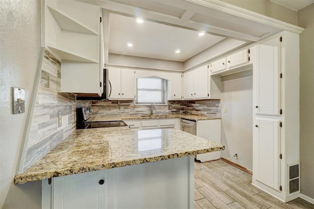 kitchen with light stone counters, stainless steel appliances, a peninsula, light wood-type flooring, and backsplash