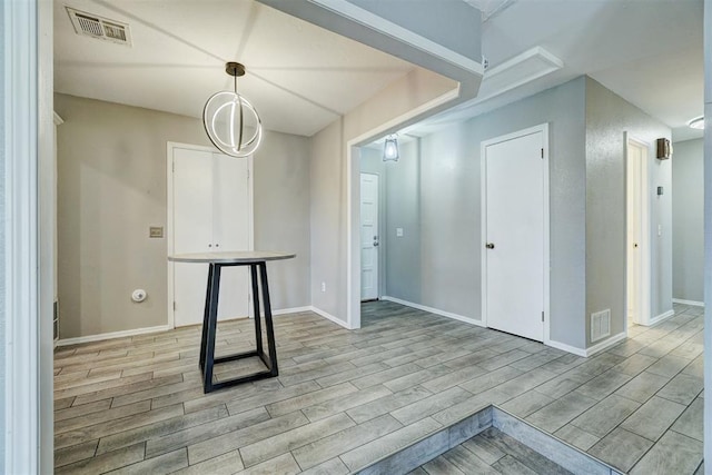 spare room featuring light wood-type flooring, visible vents, and baseboards