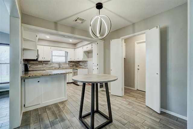 kitchen with visible vents, a peninsula, wood finish floors, white cabinetry, and backsplash