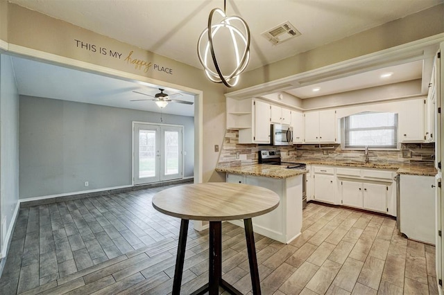 kitchen with stainless steel appliances, wood finish floors, visible vents, french doors, and decorative backsplash