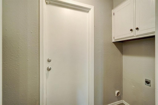 laundry room with cabinet space, a textured wall, and electric dryer hookup