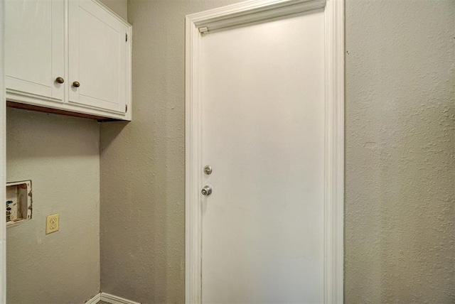 laundry room with hookup for a washing machine, cabinet space, a textured wall, and baseboards