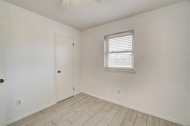 unfurnished room featuring a ceiling fan, light wood-type flooring, and baseboards