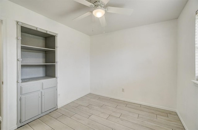 spare room featuring light wood finished floors, baseboards, and a ceiling fan