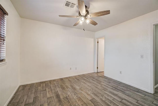 empty room featuring ceiling fan, wood finished floors, visible vents, and baseboards