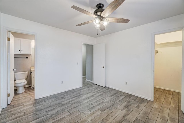 unfurnished bedroom featuring a spacious closet, wood finished floors, and baseboards