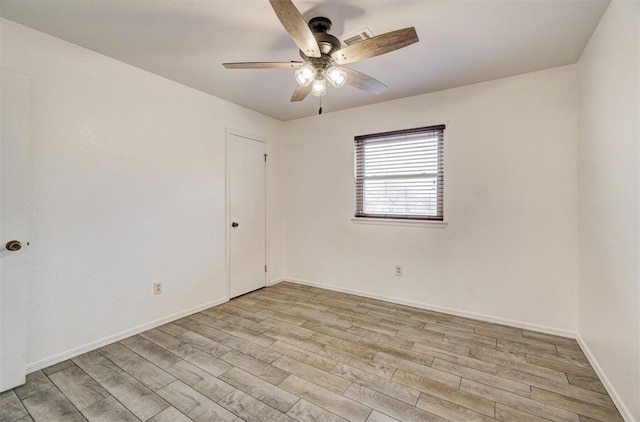 spare room with ceiling fan, visible vents, baseboards, and wood finished floors