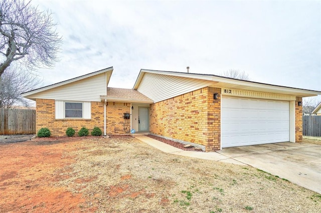 view of front of property with a garage, driveway, brick siding, and fence