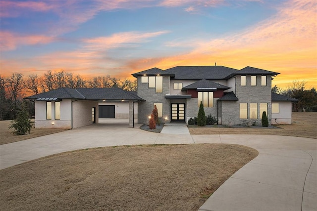 prairie-style house featuring stone siding and curved driveway