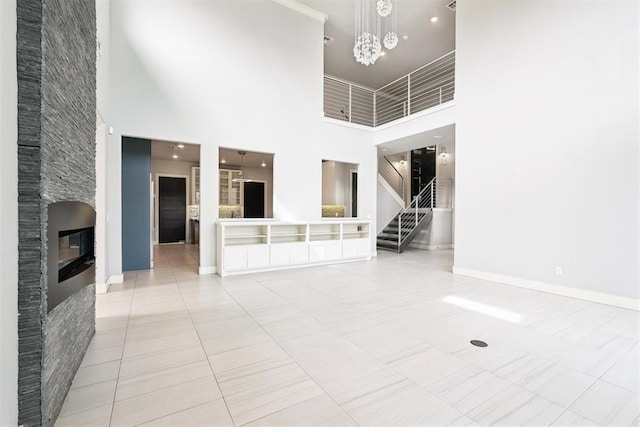 2725 Piazza Ct, Arcadia, OK 73007 - unfurnished living room featuring a high ceiling, a chandelier, tile patterned flooring, a fireplace, and stairs