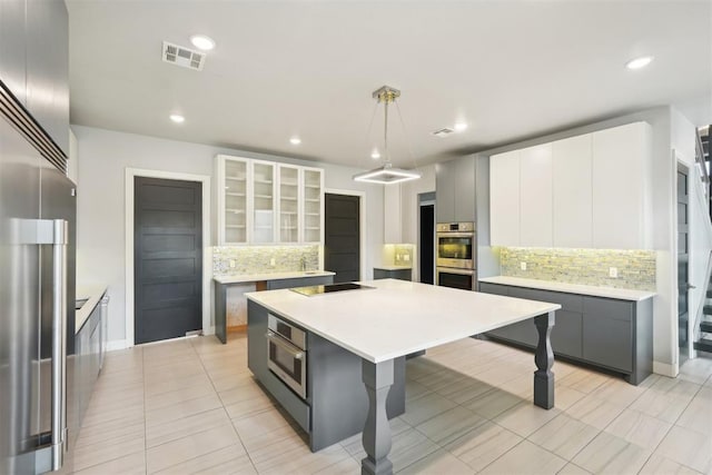 2725 Piazza Ct, Arcadia, OK 73007 - kitchen featuring stainless steel appliances, backsplash, gray cabinetry, a kitchen island, and a breakfast bar