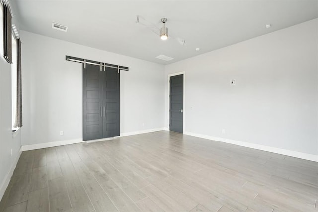 2725 Piazza Ct, Arcadia, OK 73007 - empty room with a barn door and light wood-style floors
