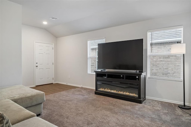 living room with lofted ceiling, carpet, visible vents, and baseboards