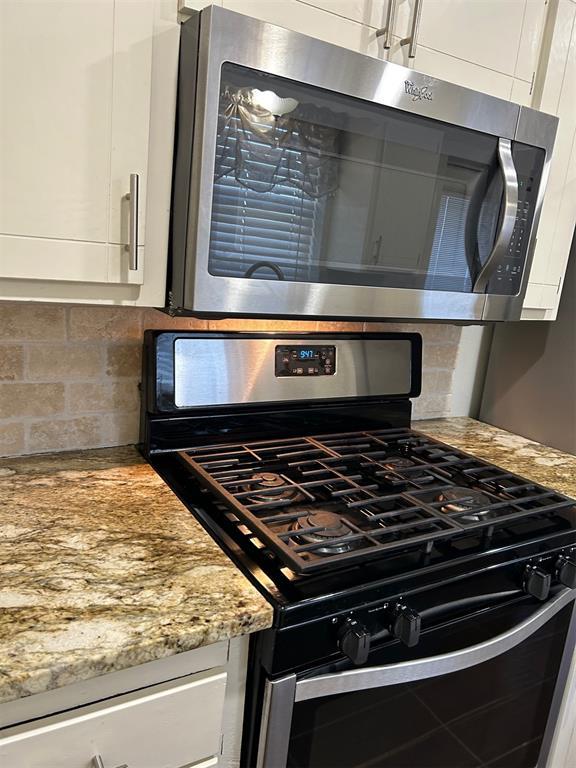 details featuring light stone countertops, tasteful backsplash, appliances with stainless steel finishes, and white cabinets