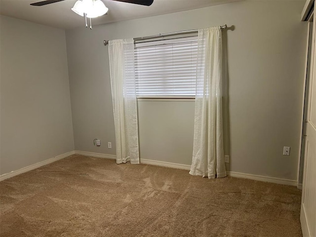 carpeted empty room with a ceiling fan and baseboards