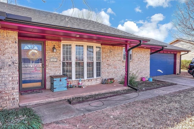 doorway to property with a garage, covered porch, roof with shingles, and driveway