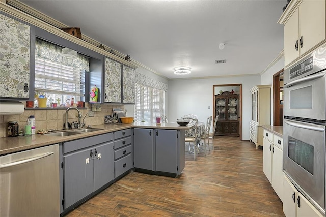 kitchen featuring stainless steel appliances, a peninsula, a sink, ornamental molding, and gray cabinets