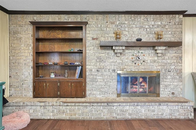 bar featuring crown molding, a textured ceiling, a fireplace, and wood finished floors