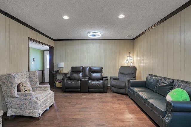 living room featuring a textured ceiling, visible vents, crown molding, and wood finished floors