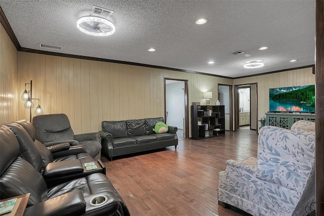 living room with ornamental molding, visible vents, a textured ceiling, and wood finished floors