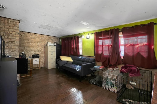 living room with a healthy amount of sunlight, brick wall, and wood finished floors