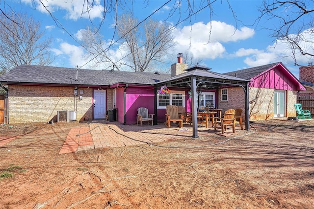 rear view of house with a patio area, a chimney, brick siding, and a gazebo