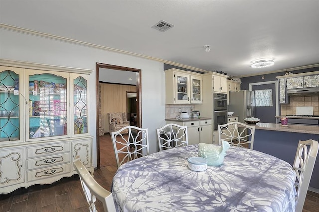 dining room featuring dark wood-style floors, visible vents, and crown molding