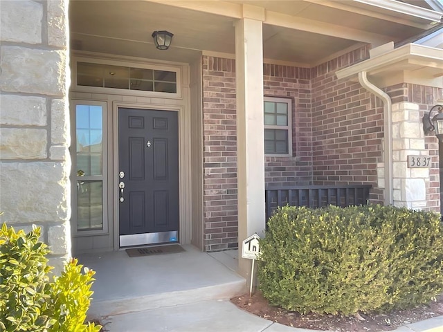 view of exterior entry featuring brick siding