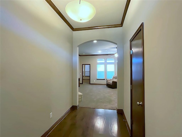 hall featuring baseboards, arched walkways, dark wood-style flooring, and ornamental molding