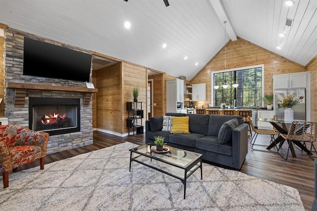 living room featuring vaulted ceiling with beams, a stone fireplace, wood walls, and wood finished floors