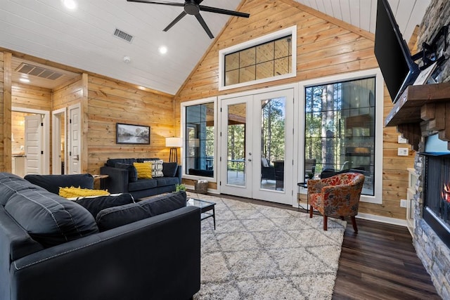 living room featuring visible vents, wood walls, and a lit fireplace