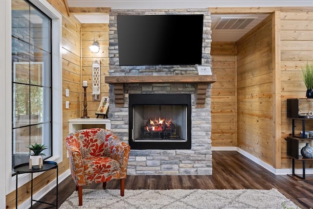 living area with wood walls, a fireplace, wood finished floors, visible vents, and baseboards