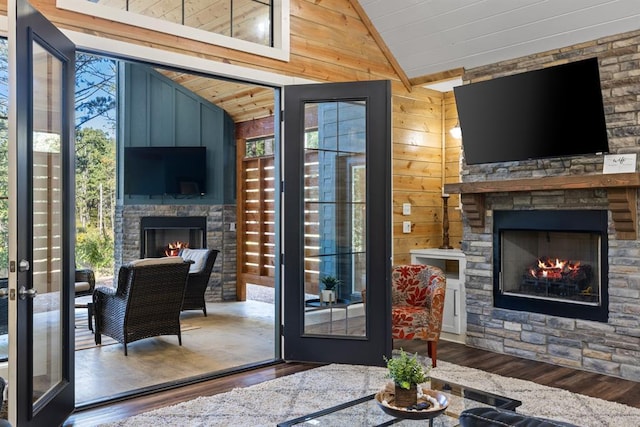 doorway with a healthy amount of sunlight, an outdoor stone fireplace, wood finished floors, and lofted ceiling