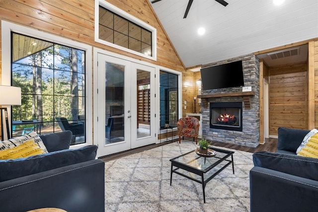 living area with plenty of natural light, wooden walls, a fireplace, and wood finished floors