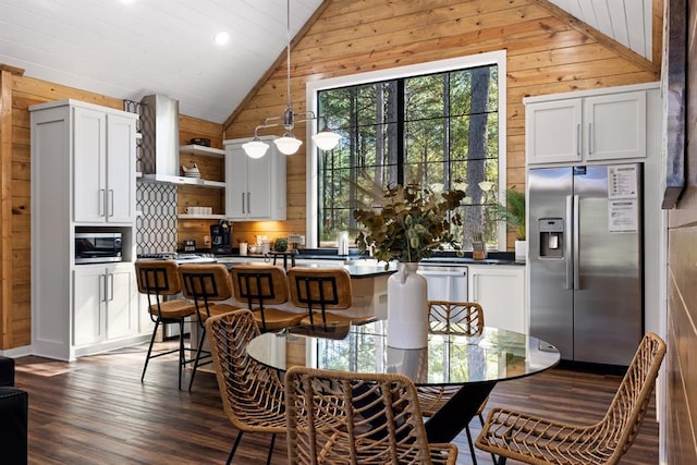 dining space featuring lofted ceiling, wood walls, dark wood finished floors, and a wealth of natural light