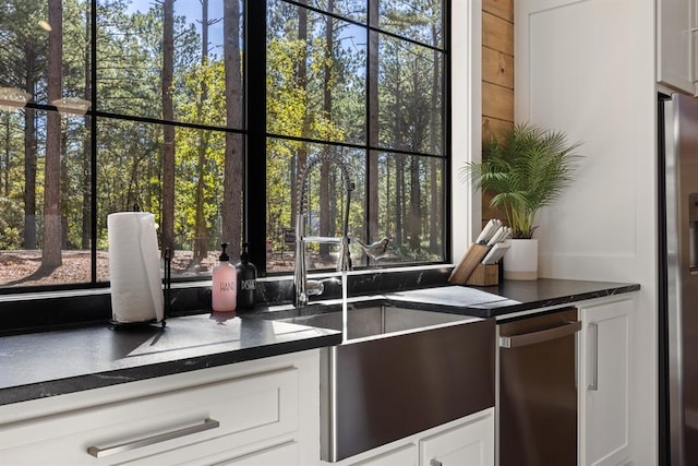 kitchen featuring dark countertops, stainless steel fridge, and white cabinets