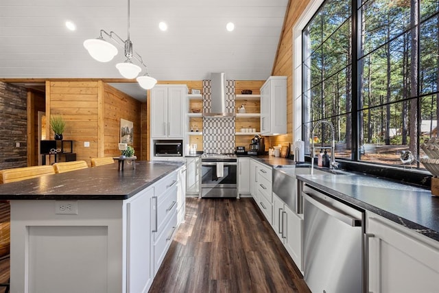 kitchen with wooden walls, wall chimney exhaust hood, stainless steel appliances, white cabinetry, and open shelves