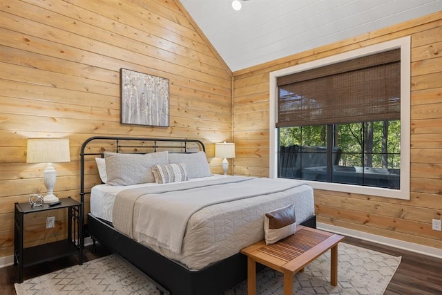 bedroom featuring lofted ceiling, wooden walls, and wood finished floors