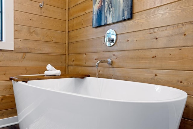 bathroom featuring a freestanding bath and wooden walls