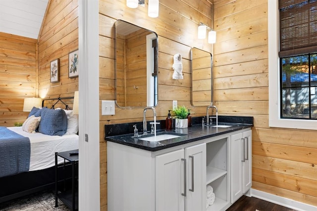 ensuite bathroom with a sink, wooden walls, ensuite bathroom, and double vanity