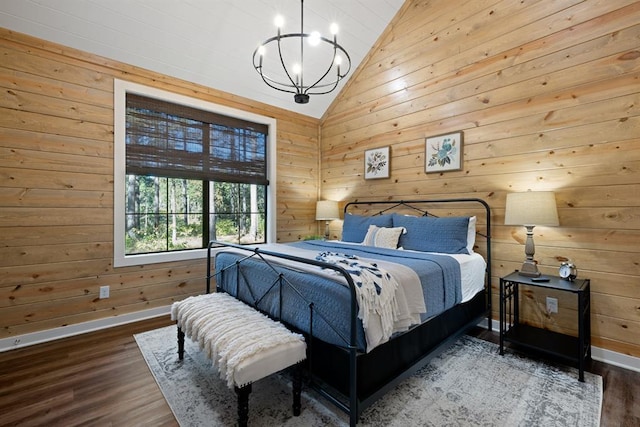 bedroom featuring lofted ceiling, an inviting chandelier, wooden walls, and wood finished floors