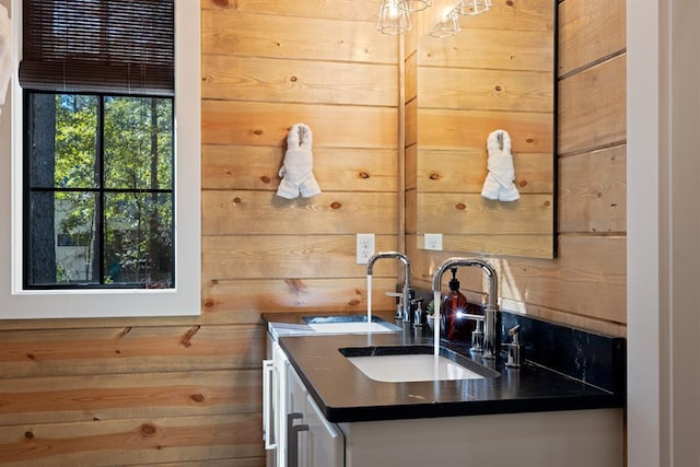 kitchen featuring dark countertops, wood walls, and a sink