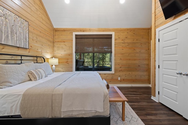 bedroom featuring vaulted ceiling, baseboards, wood finished floors, and wooden walls