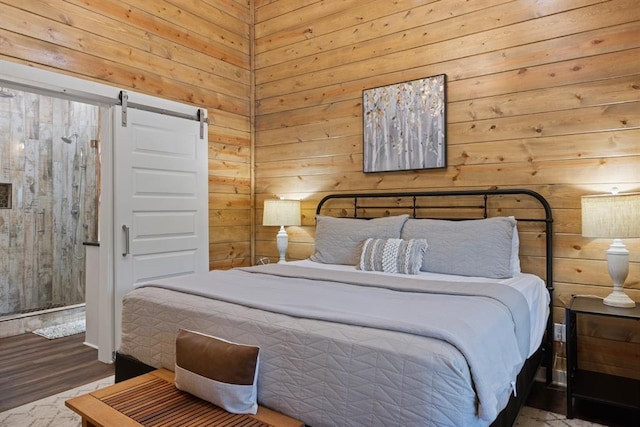 bedroom featuring wood walls, a barn door, and wood finished floors