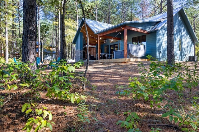 view of property exterior with metal roof, a porch, and central air condition unit