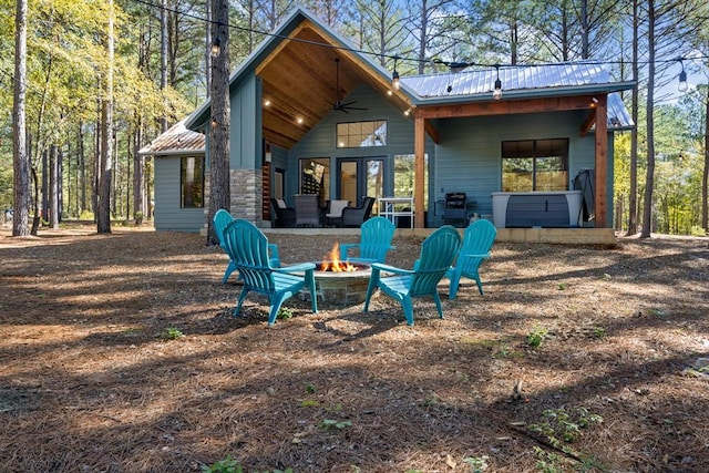 rear view of property with a fire pit, metal roof, and a patio